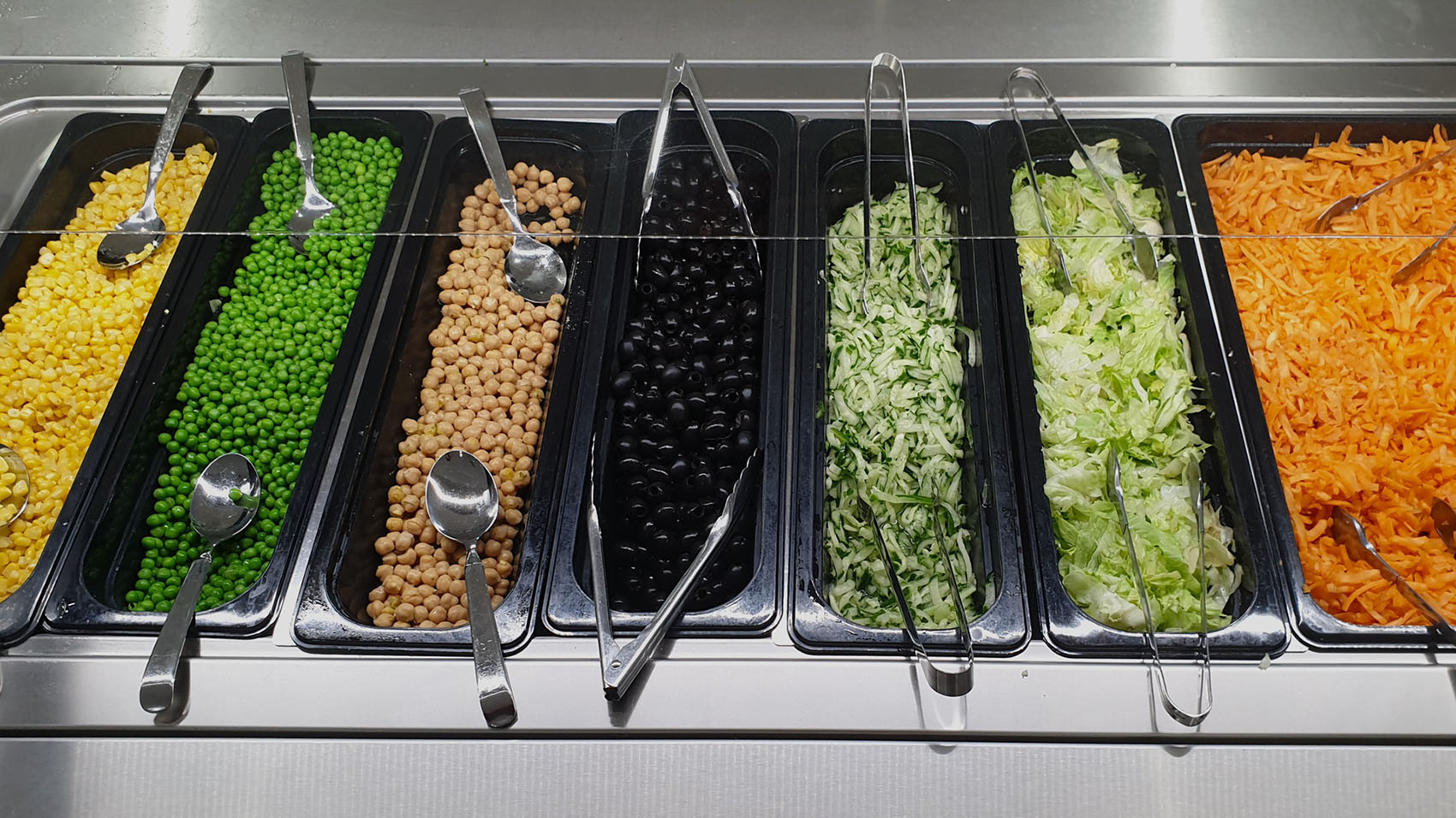 Grönsaksbuffé med bland annat rivna morötter, gröna ärtor, majs och svarta oliver.