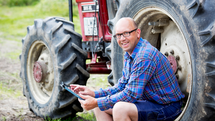 En man sitter framför en traktor. 