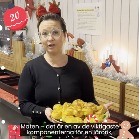 Lucka 20 i julkalendern. En kvinna står i julig utstyrsel med ett fat lussekatter i händerna