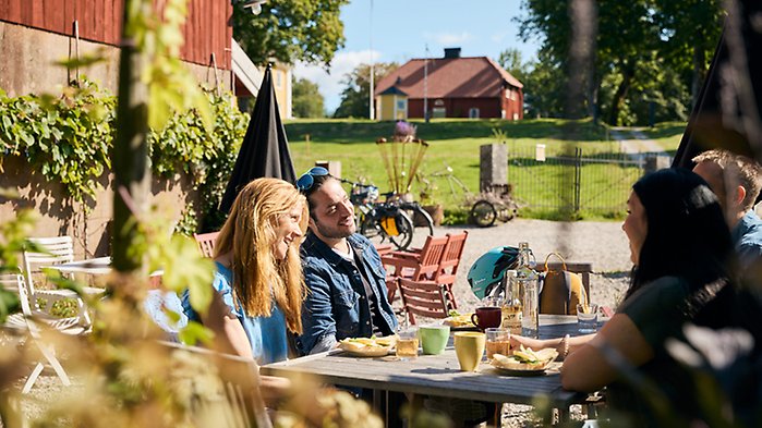 Människor som sitter vid ett cafébord i en vacker lummig miljö