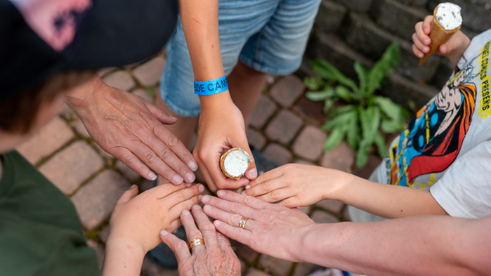 Olika människors händer som möts i mitten. En hand håller en glasstrut.