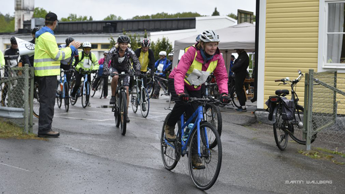 Cyklister och funktionärer i ett lopp.