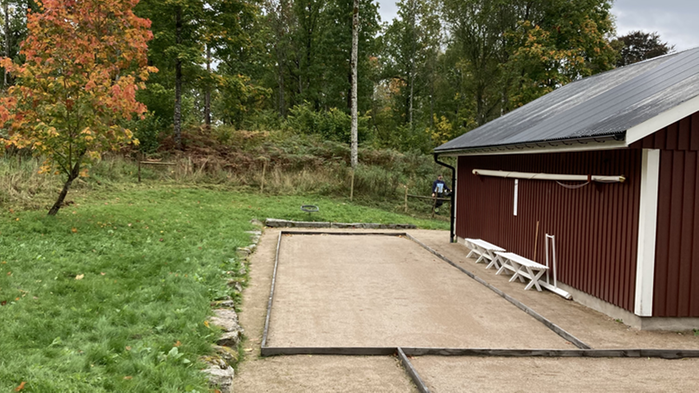 Boulebana utanför rödmålat hus.