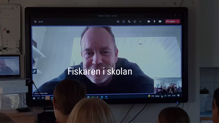 Foto på klassrum med digital skärm. Elever i samtal med Fiskaren i skolan.