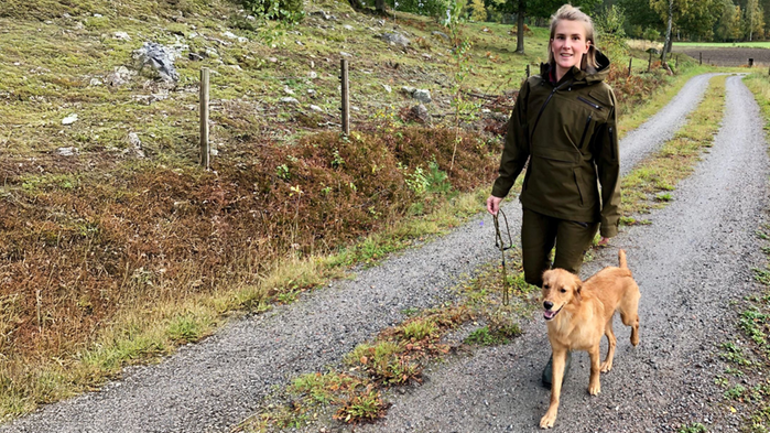 Emma Olsson har grön beige kläder och är ute och går med sin hund